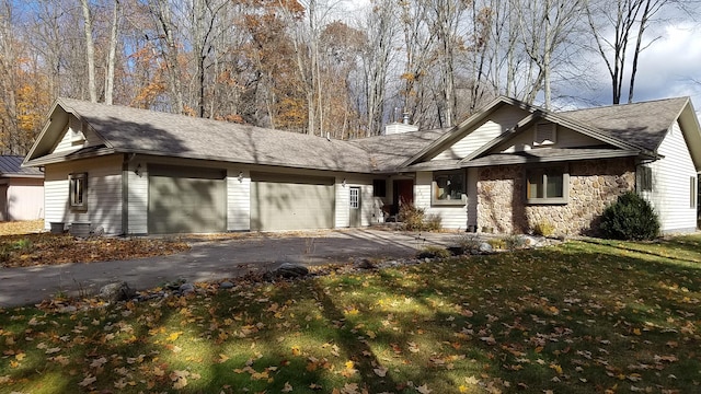 view of front of property featuring aphalt driveway, a chimney, an attached garage, stone siding, and a front lawn