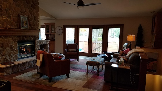 living area featuring a ceiling fan, vaulted ceiling, a fireplace, and wood finished floors