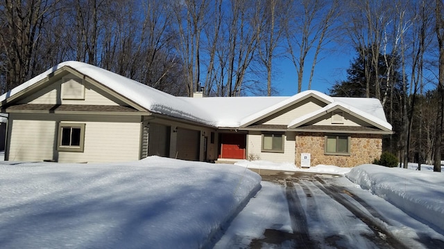 view of front of home with a garage, stone siding, and a chimney