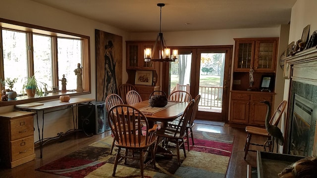 dining room featuring wood finished floors, plenty of natural light, a tiled fireplace, and an inviting chandelier