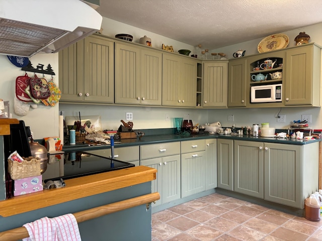 kitchen with extractor fan, a textured ceiling, white microwave, and green cabinetry