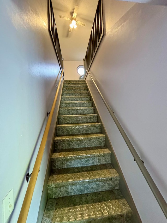 stairway featuring ceiling fan