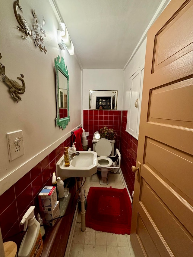 bathroom with tile walls, sink, ornamental molding, and toilet