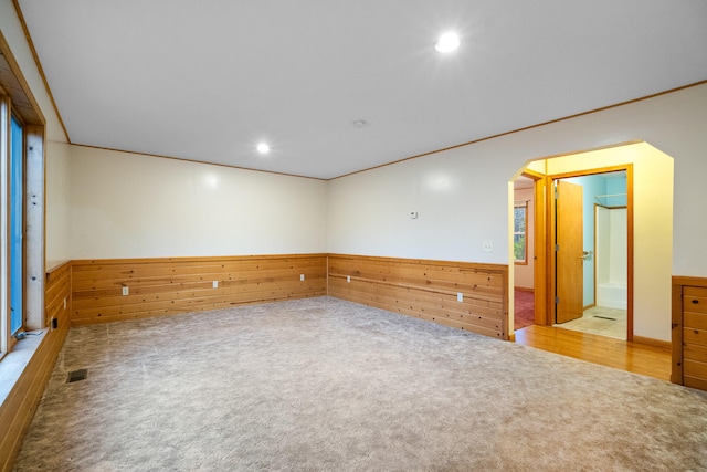 spare room with wooden walls, light carpet, and crown molding