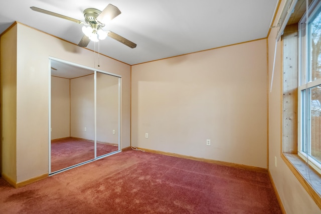 unfurnished bedroom featuring multiple windows, a closet, carpet flooring, and ceiling fan