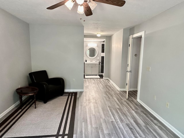 sitting room featuring a textured ceiling, light hardwood / wood-style flooring, ceiling fan, and sink