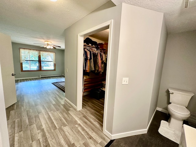 interior space featuring a baseboard heating unit, light wood-type flooring, and a textured ceiling