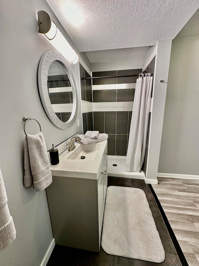 bathroom with hardwood / wood-style floors, a textured ceiling, curtained shower, and vanity