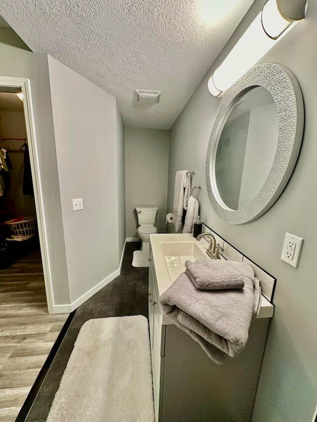 bathroom featuring hardwood / wood-style floors, vanity, a textured ceiling, and toilet