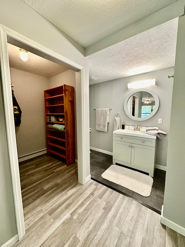 bathroom featuring vanity, hardwood / wood-style flooring, a baseboard radiator, and a textured ceiling