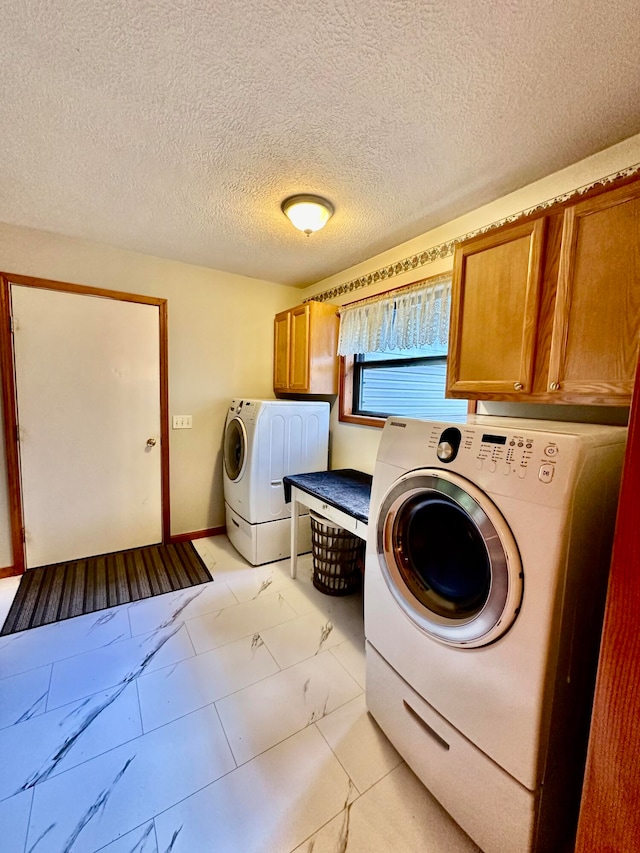 washroom featuring cabinets, a textured ceiling, and washing machine and clothes dryer