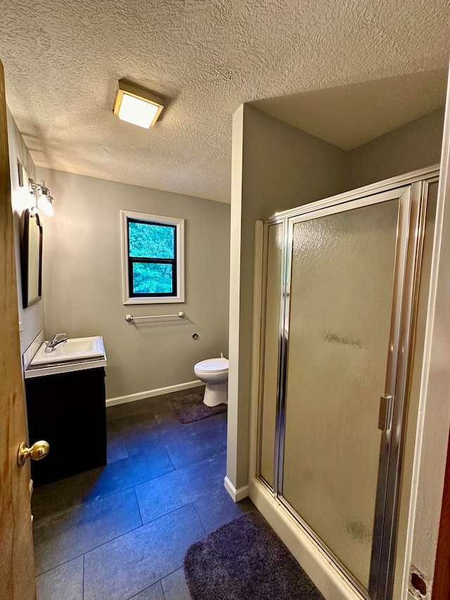 bathroom with tile patterned floors, vanity, a textured ceiling, toilet, and a shower with shower door