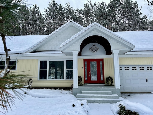 snow covered property entrance with a garage