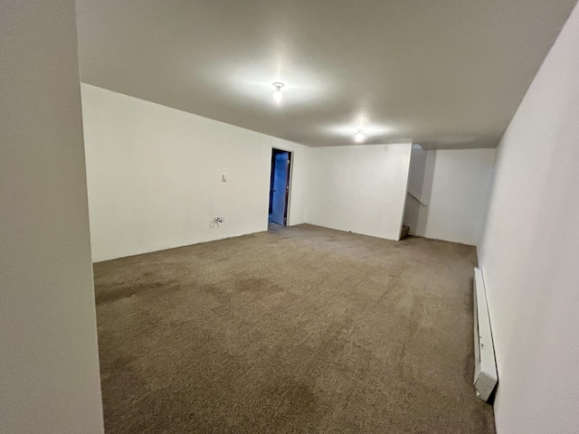 carpeted empty room featuring a baseboard heating unit