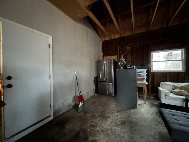 kitchen featuring stainless steel fridge, concrete flooring, and lofted ceiling