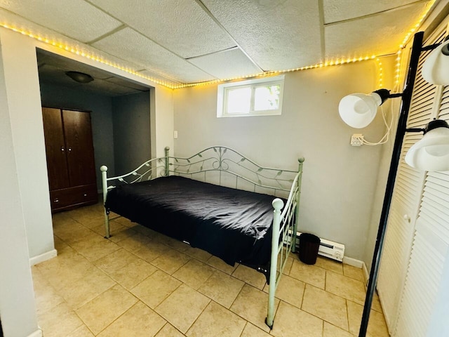 tiled bedroom with a drop ceiling and baseboards