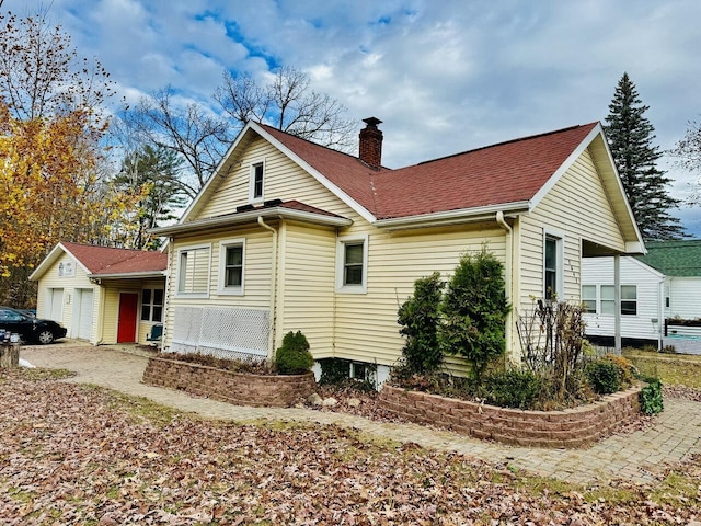 view of property exterior featuring a shingled roof, a chimney, and an attached garage