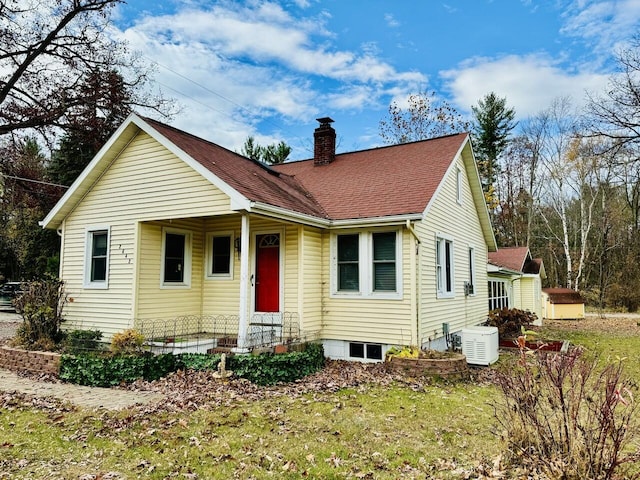 view of front of house featuring a shingled roof, a front yard, and a chimney