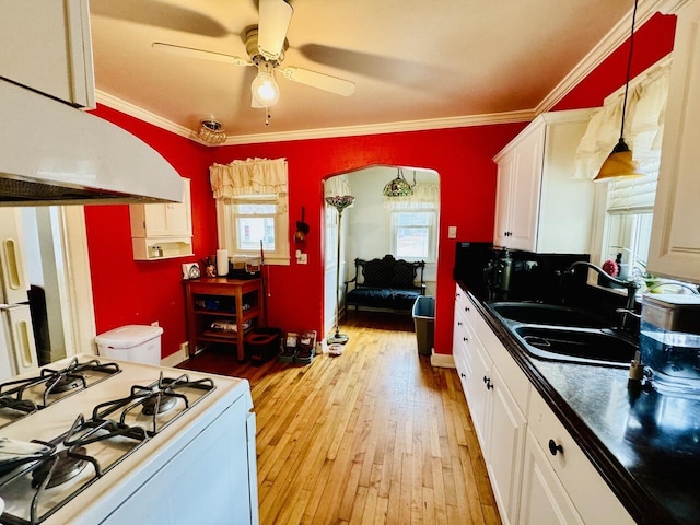 kitchen featuring dark countertops, white range with gas stovetop, white cabinetry, and a sink