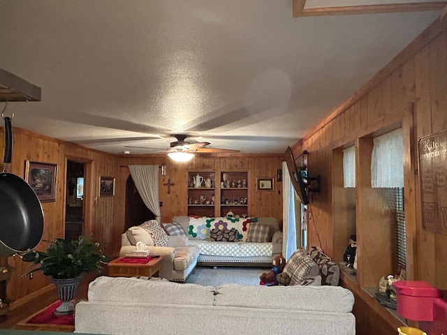 living room with wood walls, ceiling fan, and a textured ceiling