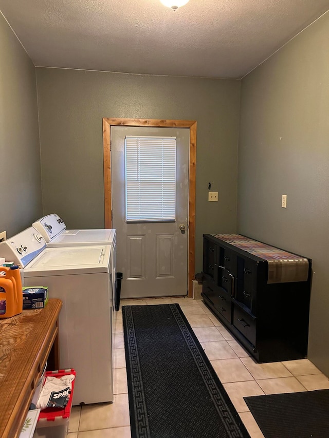 laundry room featuring a textured ceiling, light tile patterned floors, and separate washer and dryer