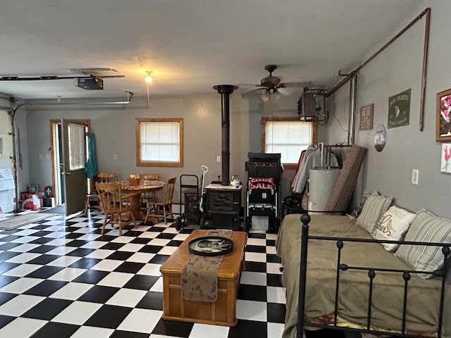 living room featuring ceiling fan, a wood stove, and a healthy amount of sunlight