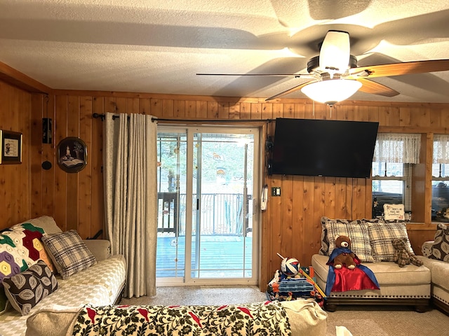 living room with wooden walls, a textured ceiling, and ceiling fan