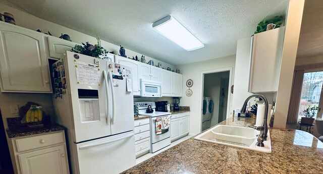 kitchen with white appliances, sink, independent washer and dryer, a textured ceiling, and white cabinetry