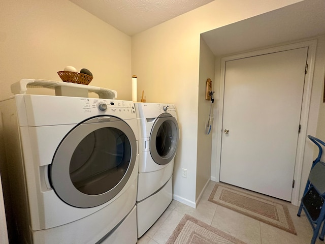 washroom with a textured ceiling, light tile patterned flooring, and washing machine and clothes dryer