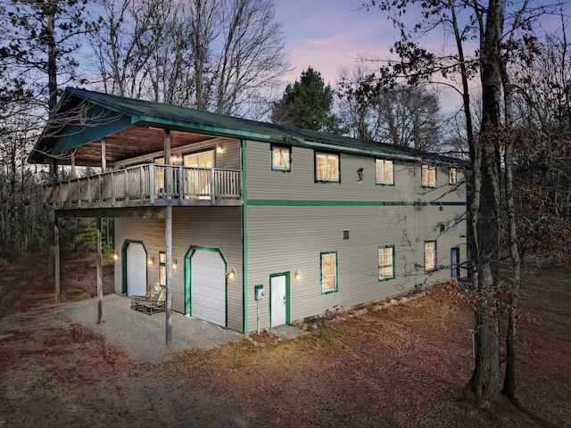 back house at dusk featuring a wooden deck and a garage