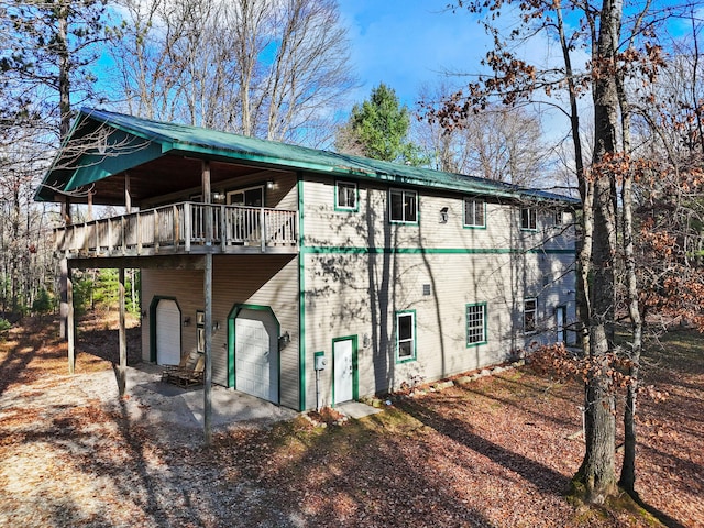 back of property with a wooden deck and a garage