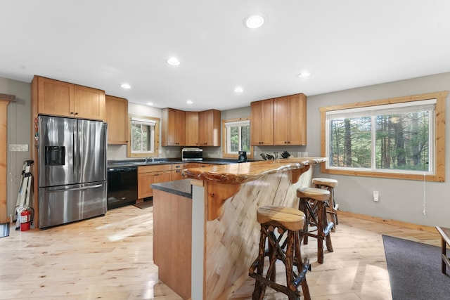 kitchen with sink, black dishwasher, stainless steel fridge with ice dispenser, light hardwood / wood-style floors, and a breakfast bar area