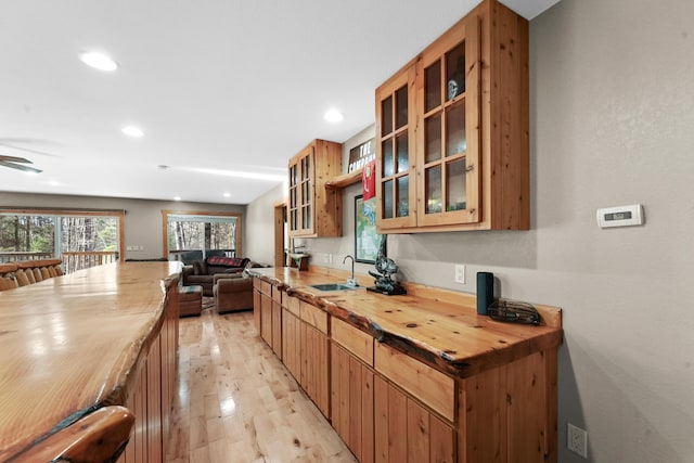 kitchen with butcher block counters, ceiling fan, sink, and light wood-type flooring