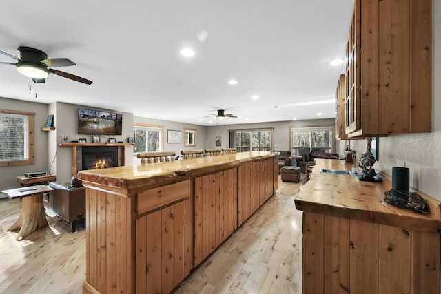 kitchen with butcher block counters, ceiling fan, sink, light hardwood / wood-style floors, and a kitchen island