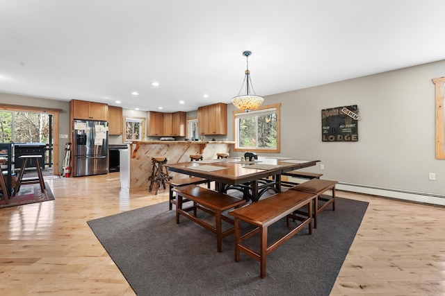 dining area featuring light hardwood / wood-style floors, plenty of natural light, and a baseboard heating unit