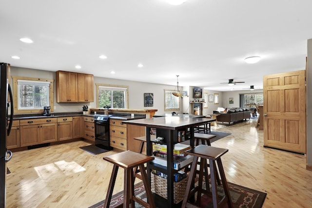 kitchen featuring pendant lighting, refrigerator, black range with electric stovetop, ceiling fan, and light hardwood / wood-style floors