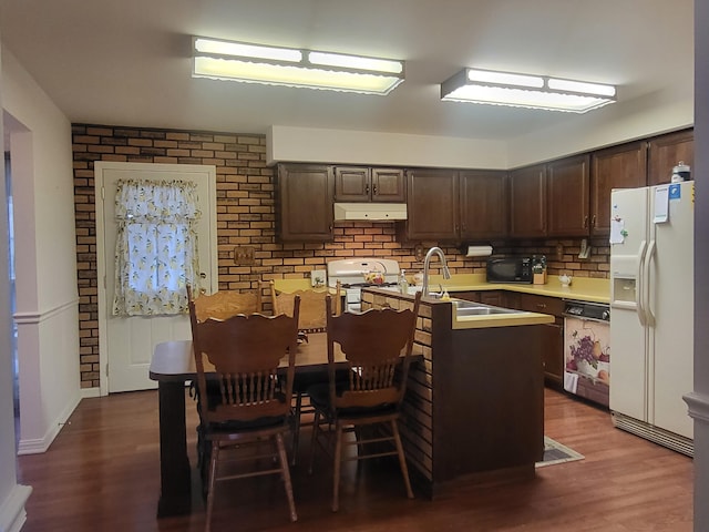 kitchen with dark brown cabinetry, kitchen peninsula, backsplash, white appliances, and dark wood-type flooring