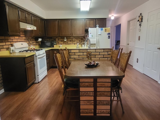 kitchen featuring white appliances, a kitchen bar, light hardwood / wood-style flooring, and decorative backsplash