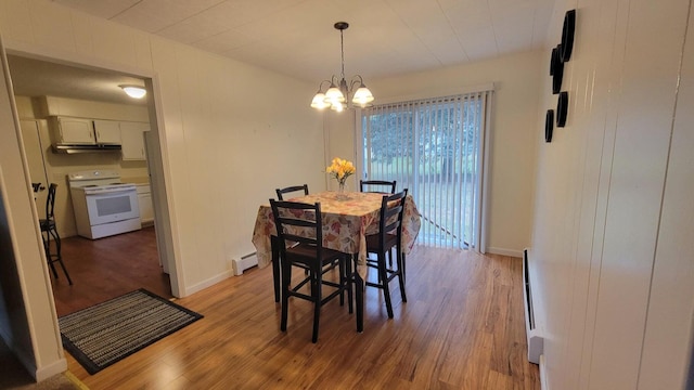 dining room featuring baseboard heating, light hardwood / wood-style flooring, and an inviting chandelier