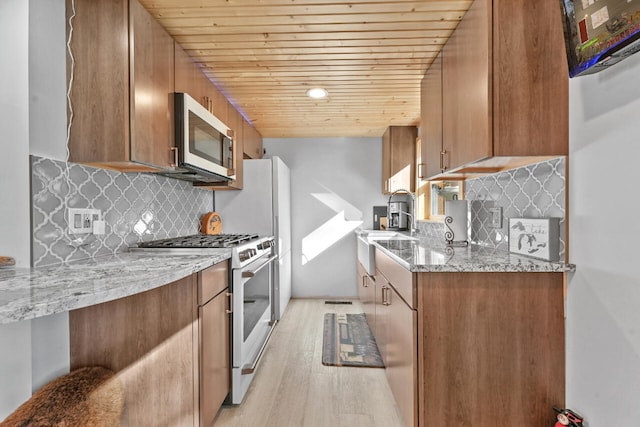 kitchen featuring tasteful backsplash, light stone countertops, wood ceiling, high end white range oven, and light wood-type flooring