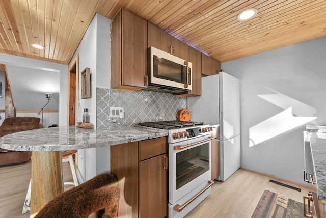 kitchen with white appliances, a breakfast bar area, wood ceiling, and light hardwood / wood-style flooring