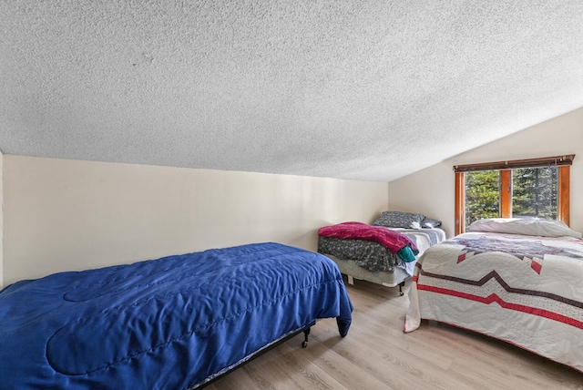 bedroom featuring hardwood / wood-style floors, a textured ceiling, and vaulted ceiling