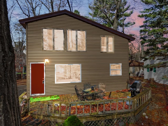 back house at dusk featuring a deck