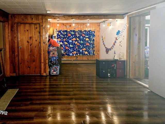 spare room featuring dark hardwood / wood-style flooring, wooden walls, and a baseboard heating unit