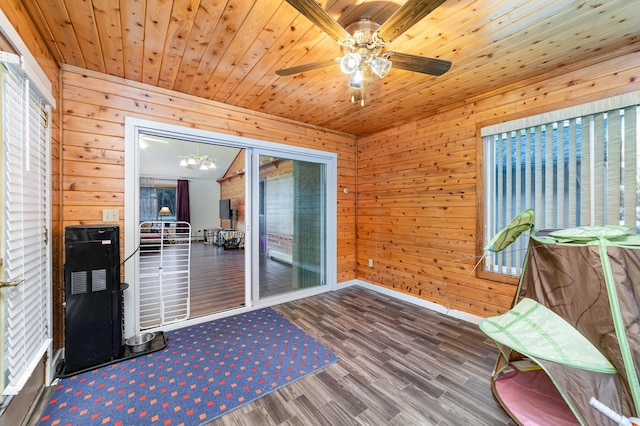 living area with ceiling fan with notable chandelier, wooden ceiling, wood walls, and hardwood / wood-style floors