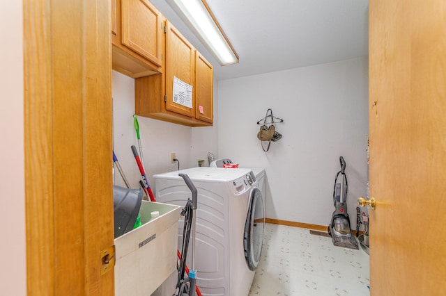 laundry area with washing machine and dryer, cabinets, and sink