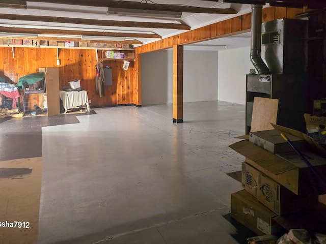 basement featuring electric panel, heating unit, and wood walls