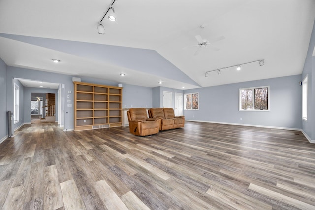 unfurnished room with hardwood / wood-style floors, rail lighting, ceiling fan, and lofted ceiling