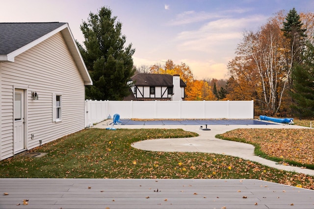 yard at dusk featuring a swimming pool side deck and a patio area