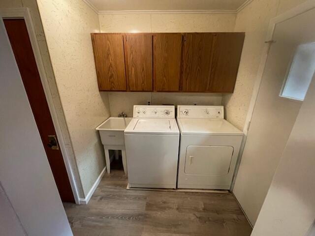 clothes washing area featuring dark hardwood / wood-style flooring, cabinets, washing machine and clothes dryer, and crown molding